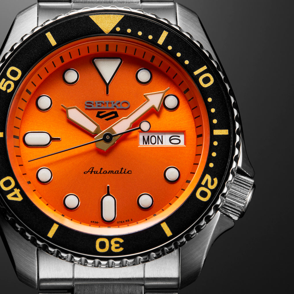 Seiko 5 Sports Automatic Watch with an Orange Dial, Black Bezel, and Silver Tone Stainless Steel Metal Band