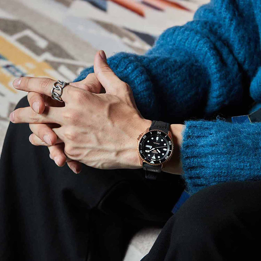 A Man Sitting with Fingers locked Showing His Seiko 5 Sports Automatic Watch SRPD76K1